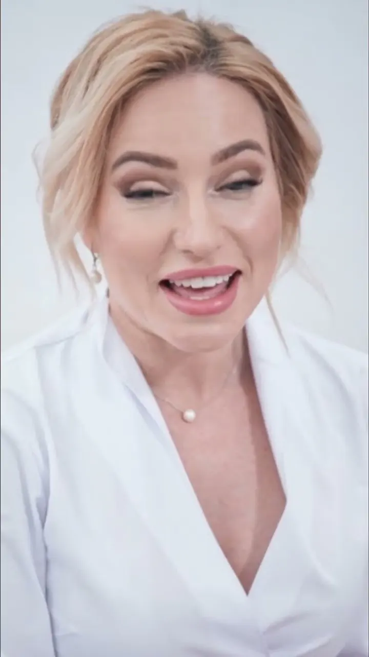A presenter in white speaking directly to camera.
